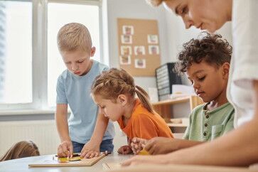 Montessori Method showing 3 kids working with their Montessori teacher with a wooden toy